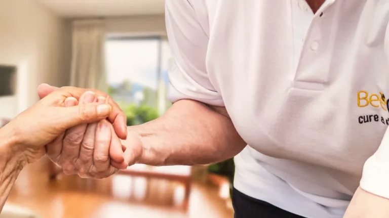 BeeCare-Mitarbeiterin hält die Hand einer älteren Person und bietet dadurch Unterstützung und Geborgenheit bei der häuslichen Pflege.